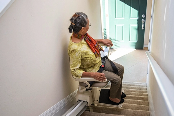 a woman using a chair lift after receiving a Chair Lift Repair in Hagerstown, MD, Baltimore, Silver Spring, Bel Air, MD, Dundalk, MD, Pasadena, MD